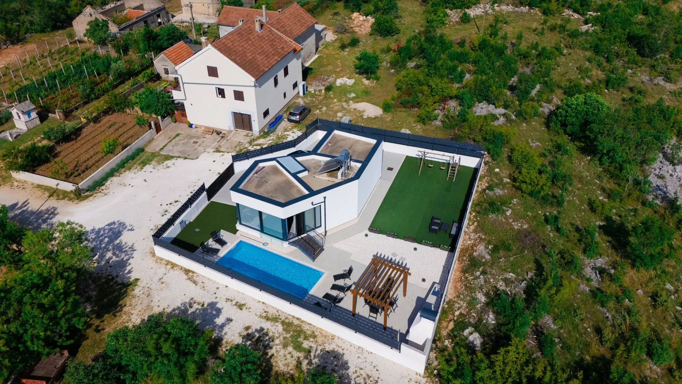 Luftaufnahme eines Wohnhauses mit Pool, umgeben von Grünflächen