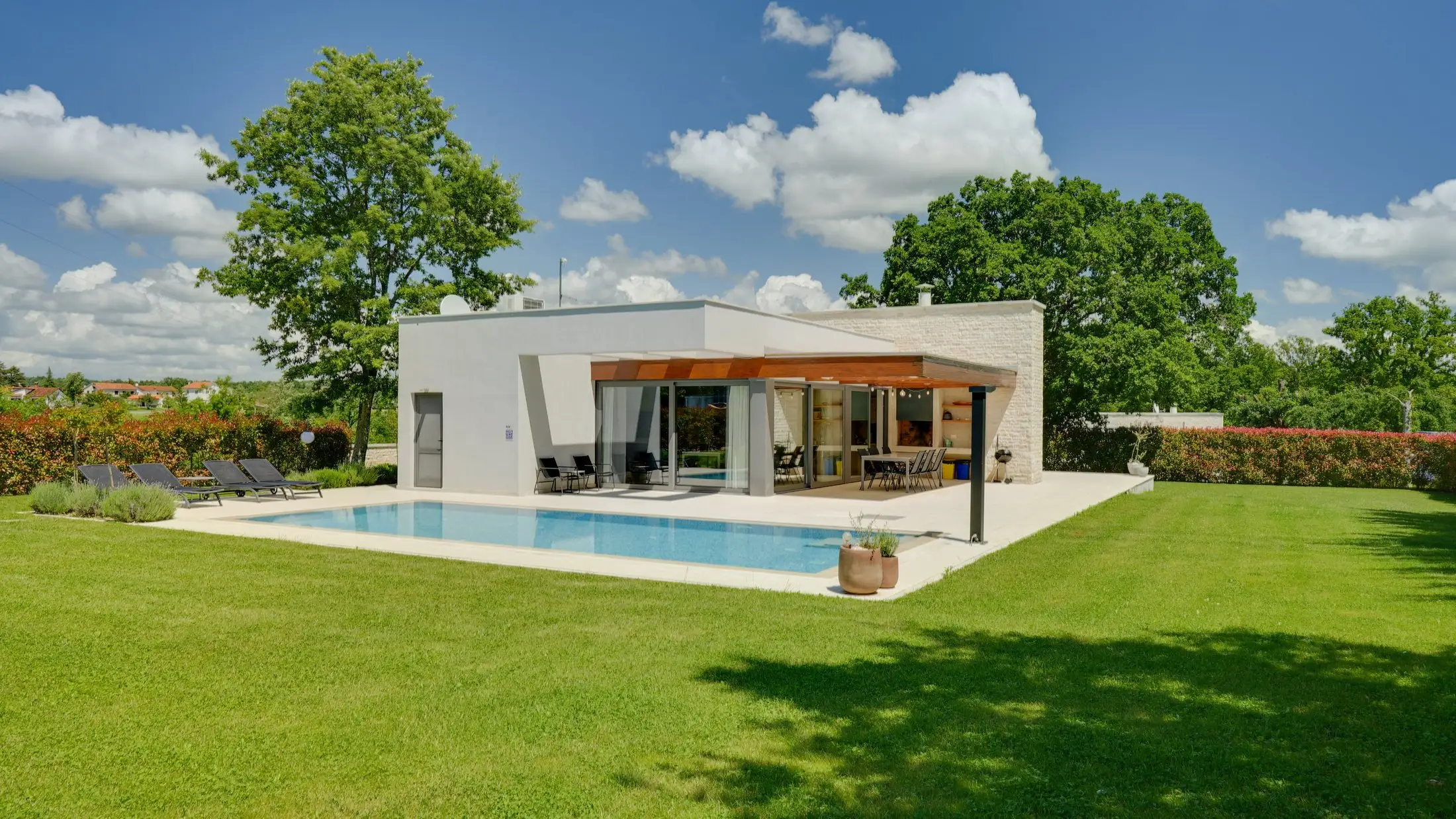 Modernes Wohnhaus mit Pool und Rasenfläche in der Sommersonne