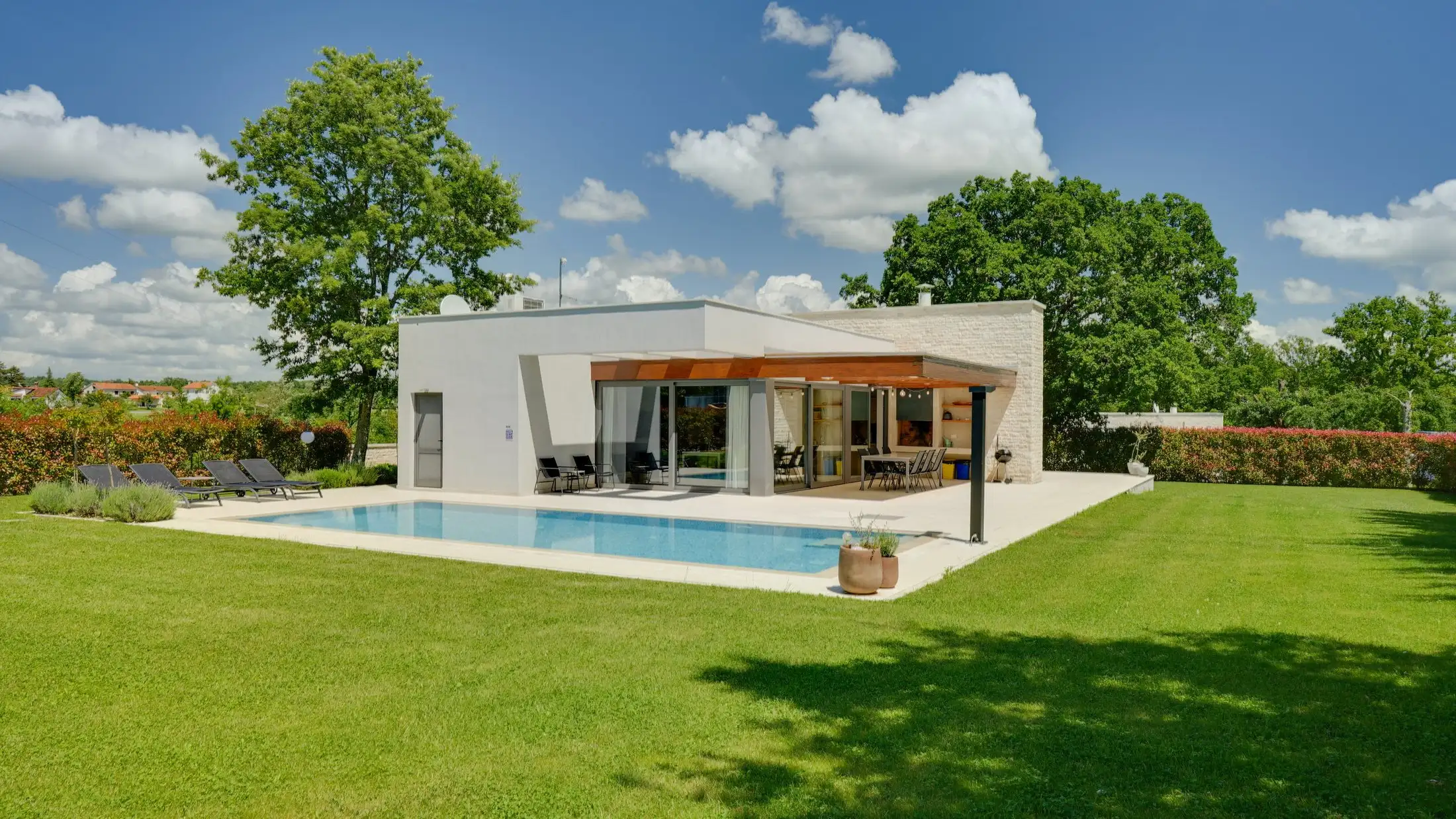 Modernes Wohnhaus mit Pool und Rasenfläche, aufgenommen für die Immobilienvermarktung