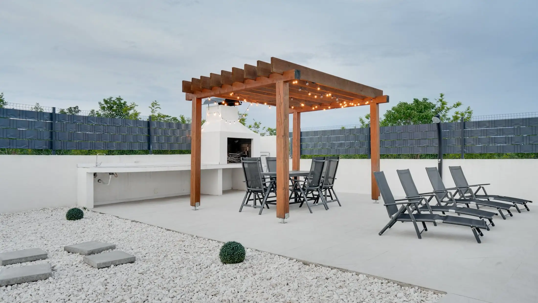 Terrasse mit Pergola und Liegestühlen an einem Wohnhaus