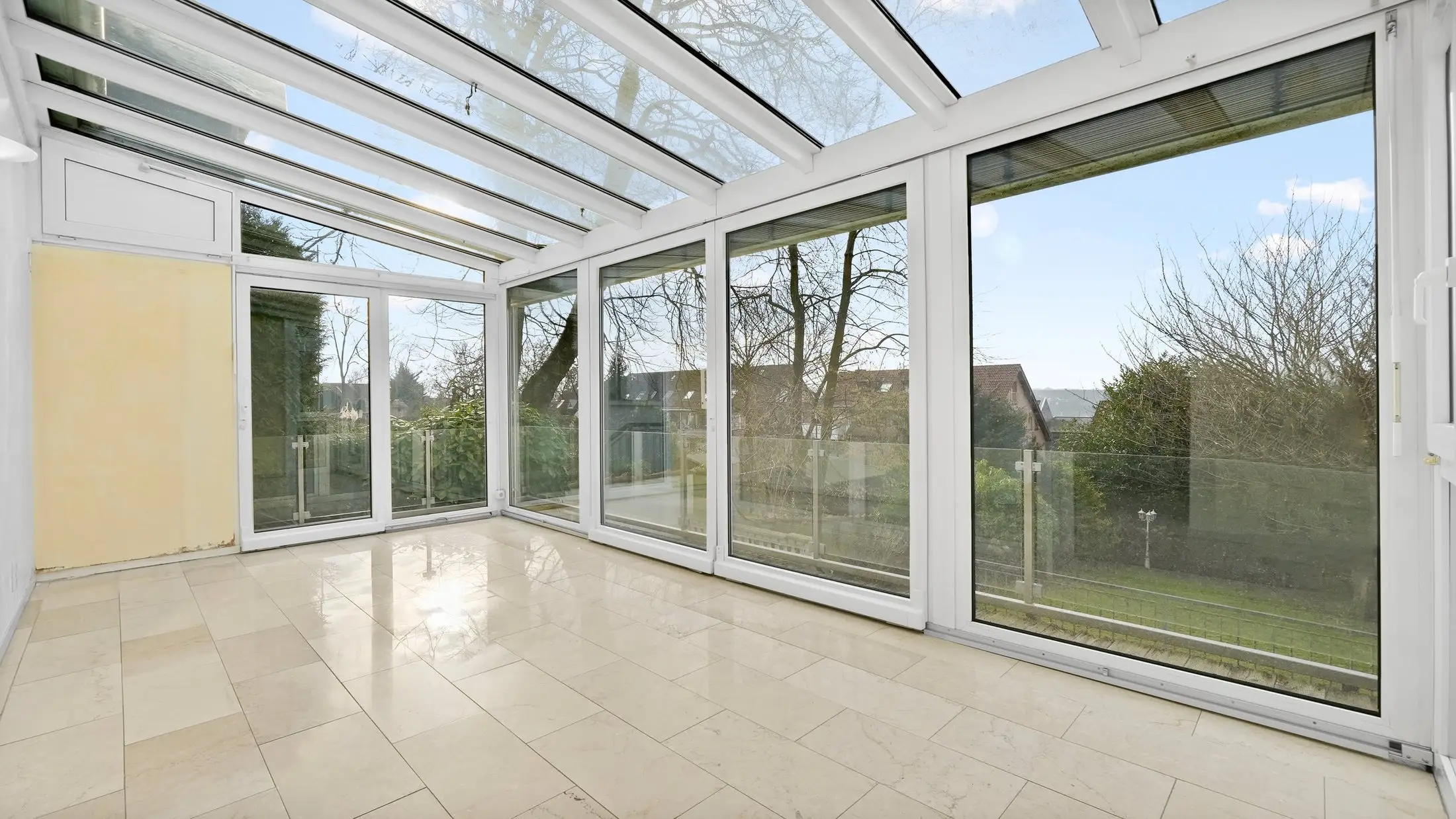 Heller Wintergarten mit umlaufender Verglasung und Blick ins Grüne